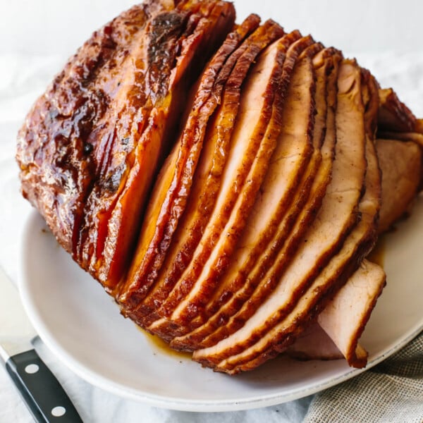 Honey baked ham on a plate next to a knife