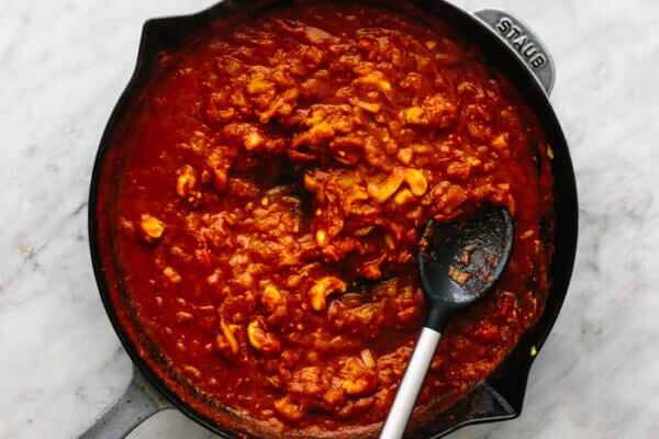 Butter chicken curry sauce in a large pan with spoon.