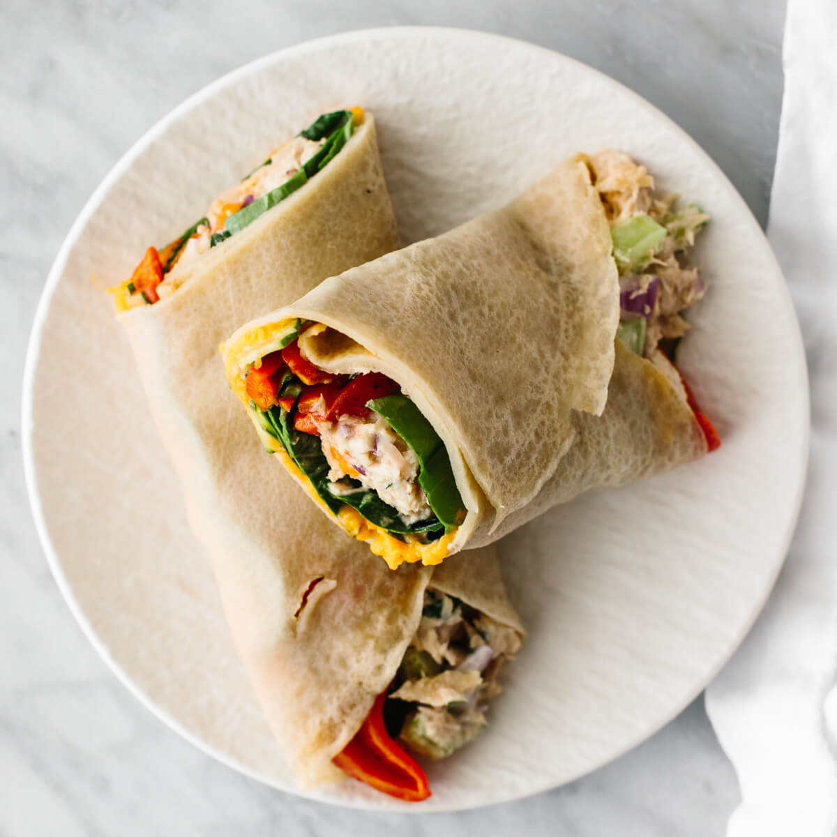 This budget meal prep shows that healthy eating doesn't have to break the bank. Turn 11 prepped ingredients into 7 meals that costs $3 or less! Tuna salad wrap on a plate for a budget meal prep