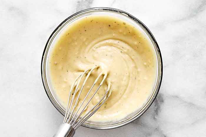 Whisking together a maple mustard tahini dressing.