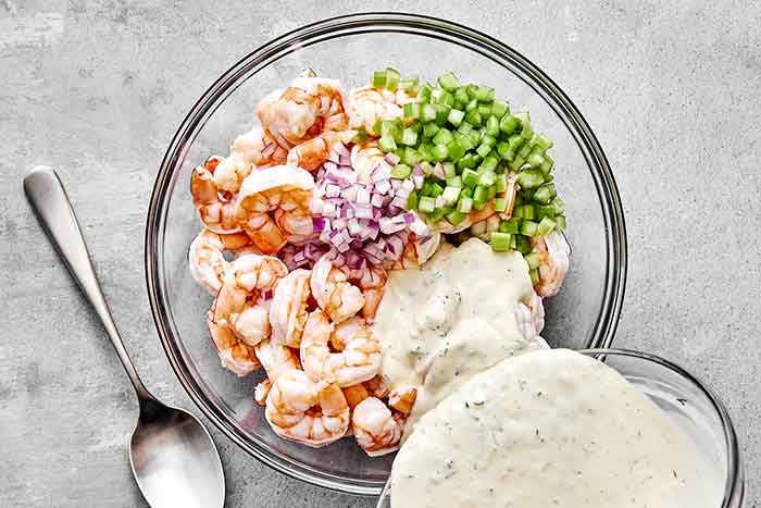 Adding dressing to a shrimp salad.