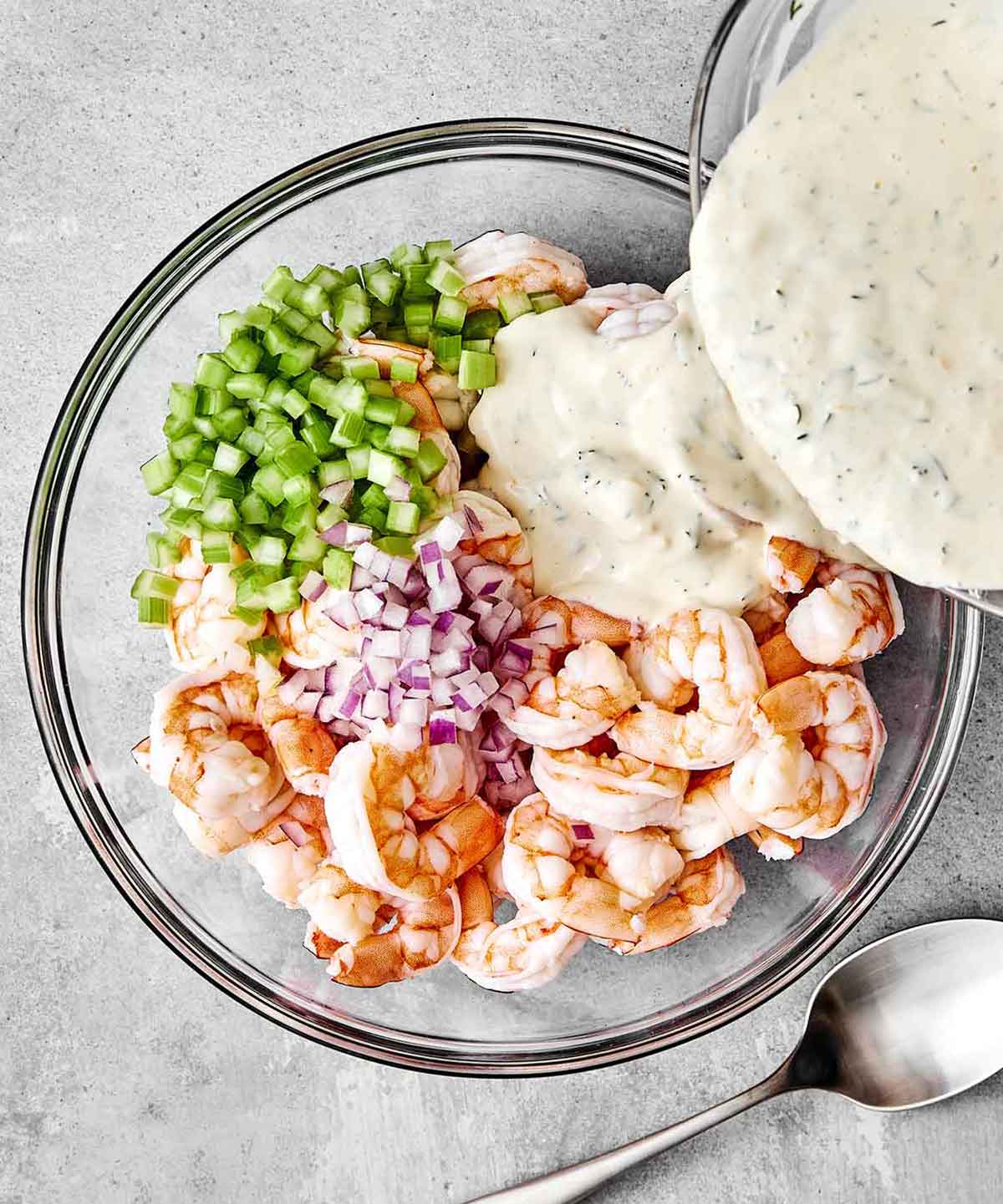 Adding dressing to a shrimp salad.
