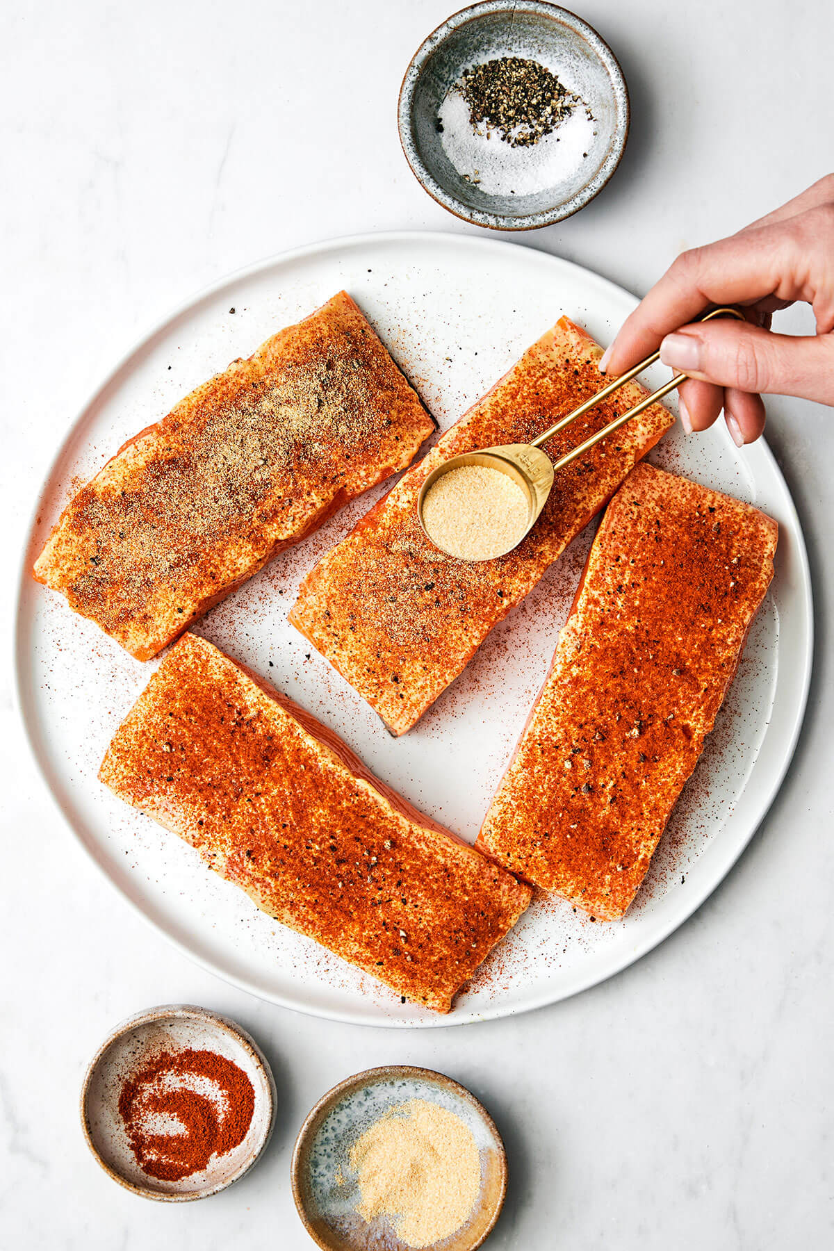 This air fryer salmon recipe is the secret to a moist and crispy filet that tastes like a million bucks - in under 15 minutes! Adding seasoning to salmon filets.