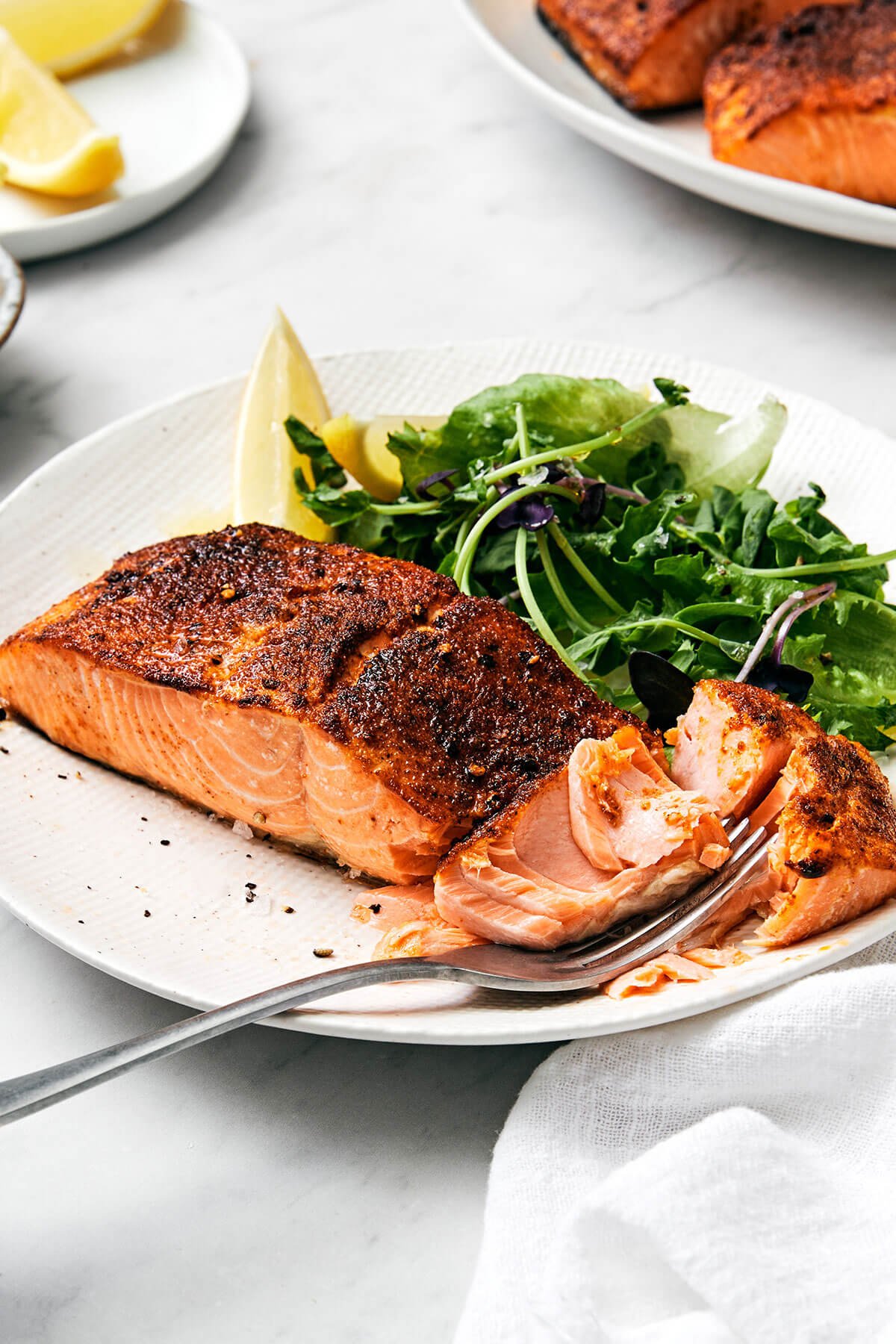This air fryer salmon recipe is the secret to a moist and crispy filet that tastes like a million bucks - in under 15 minutes! Air fryer salmon on a plate with a fork.