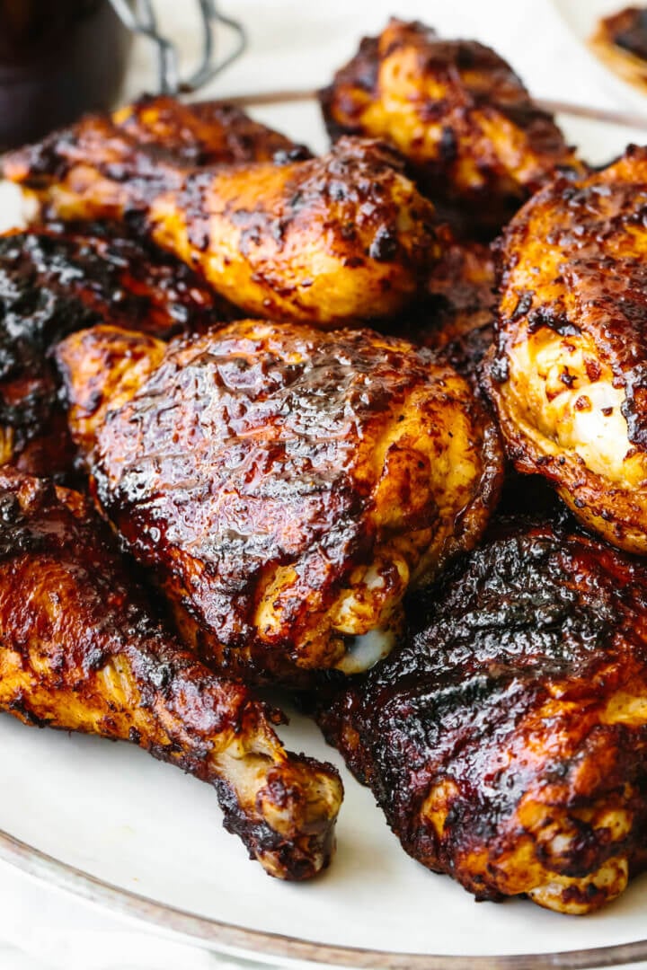 This BBQ chicken is insanely juicy, perfectly charred, and glistening with my secret homemade BBQ sauce. Perfect for your summer cookout! A plate of BBQ chicken