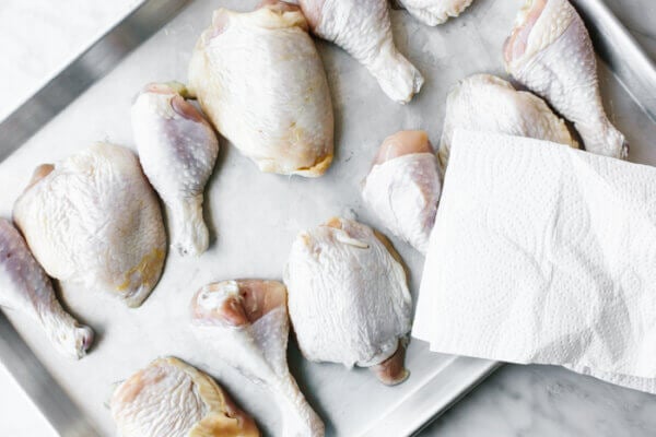 Patting chicken dry on a sheet pan before barbecuing