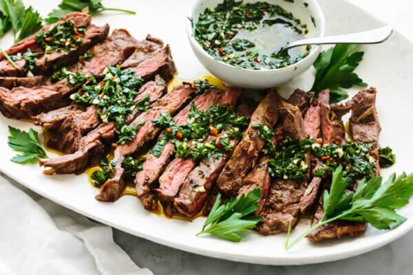 Skirt steak recipe topped with chimichurri sauce on a platter