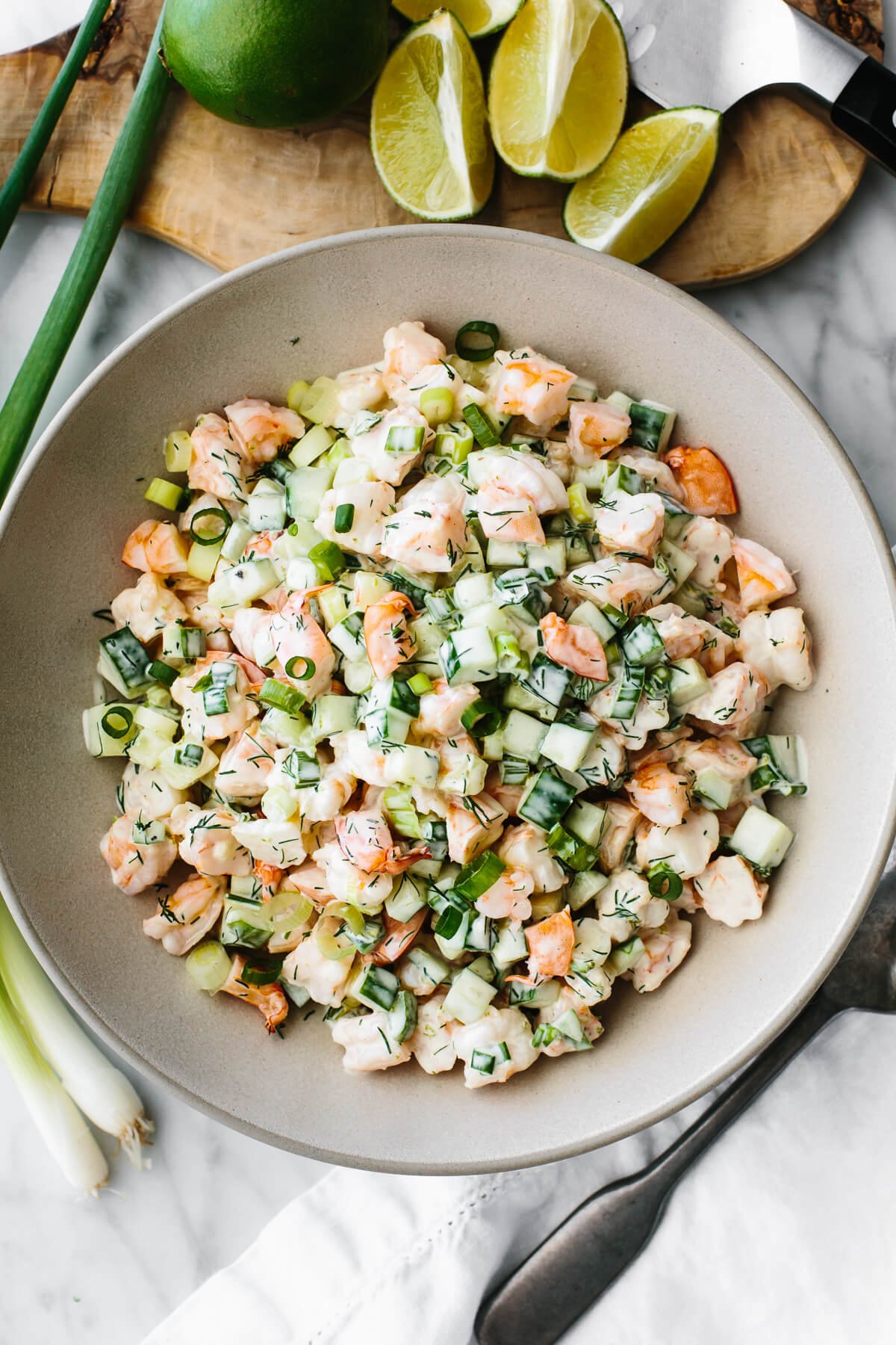 This cucumber shrimp salad is everything you love about an easy and healthy salad recipe, but with a fresh twist! Cucumber shrimp salad in a large serving bowl next to limes