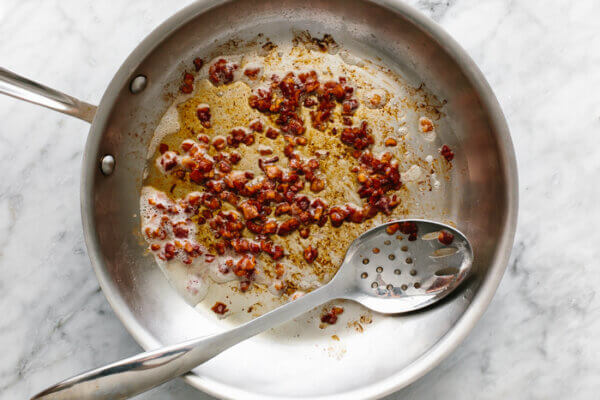 A pan with cooked bacon for sauteed carrots