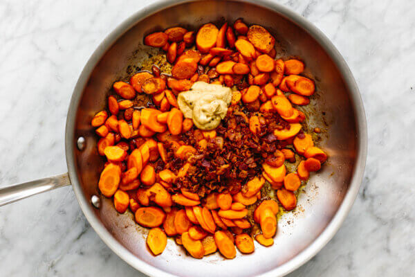 Tossing sauteed carrots with a bacon Dijon dressing