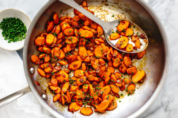 Sauteed carrots in a pan with a large spoon