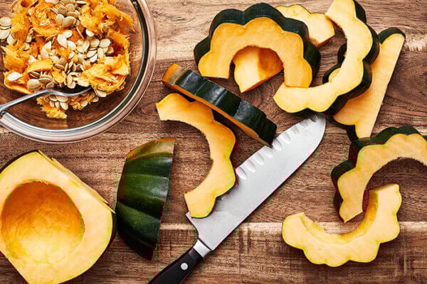 Slicing acorn squash on a wooden cutting board