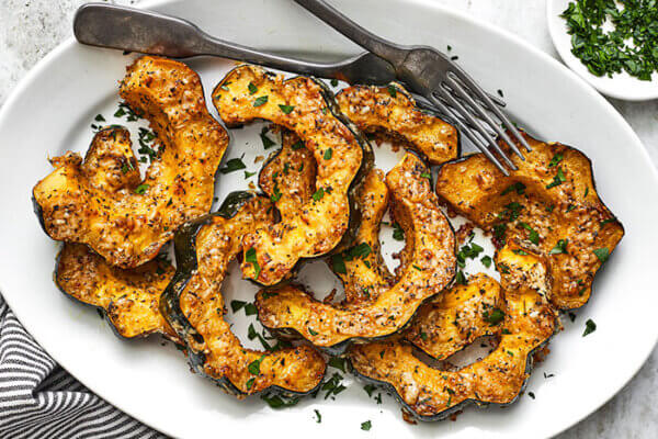 A white plate of parmesan herb roasted acorn squash
