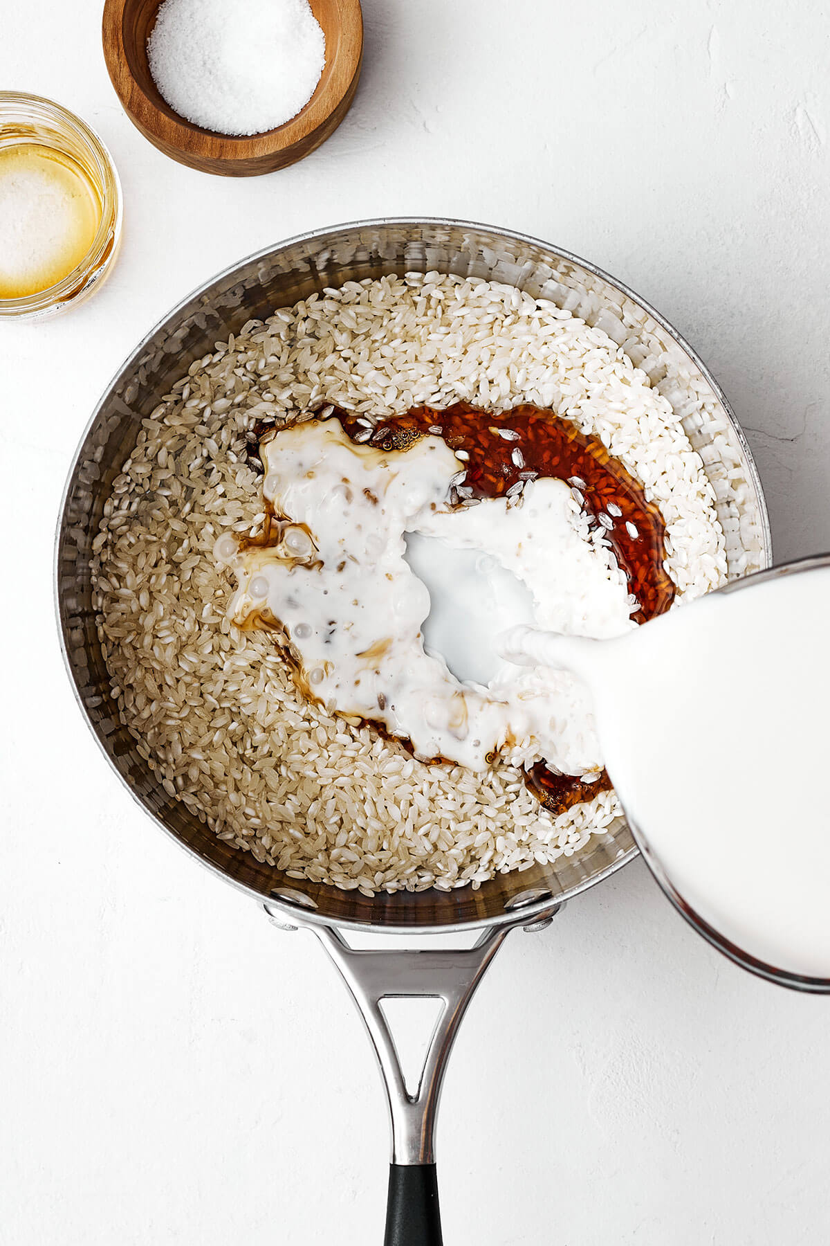 Pouring milk into a pot with rice to make rice pudding