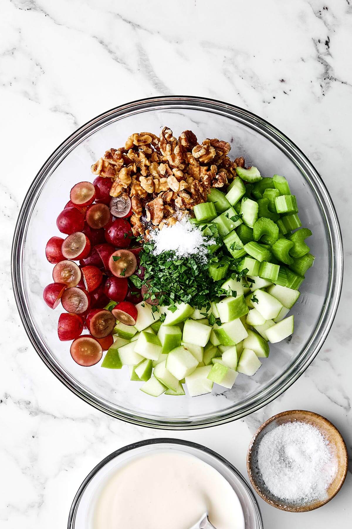 Everyone will love this classic Waldorf salad for holiday dinners! It's crisp, refreshing, and tossed in the best creamy dressing. Mixing Waldorf salad in a bowl.