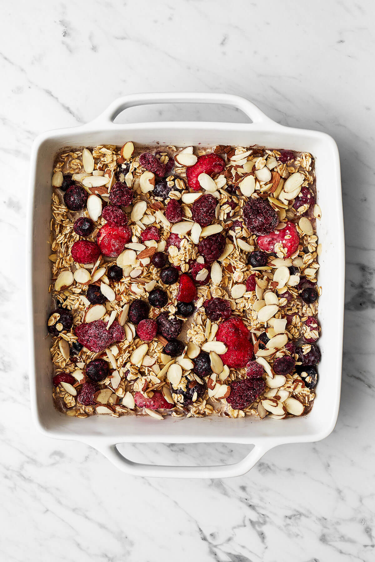 This berry baked oatmeal is the perfect breakfast meal prep! It's got a golden outside and soft inside and is loaded with sweet berries. Berry baked oatmeal in a baking dish before baking