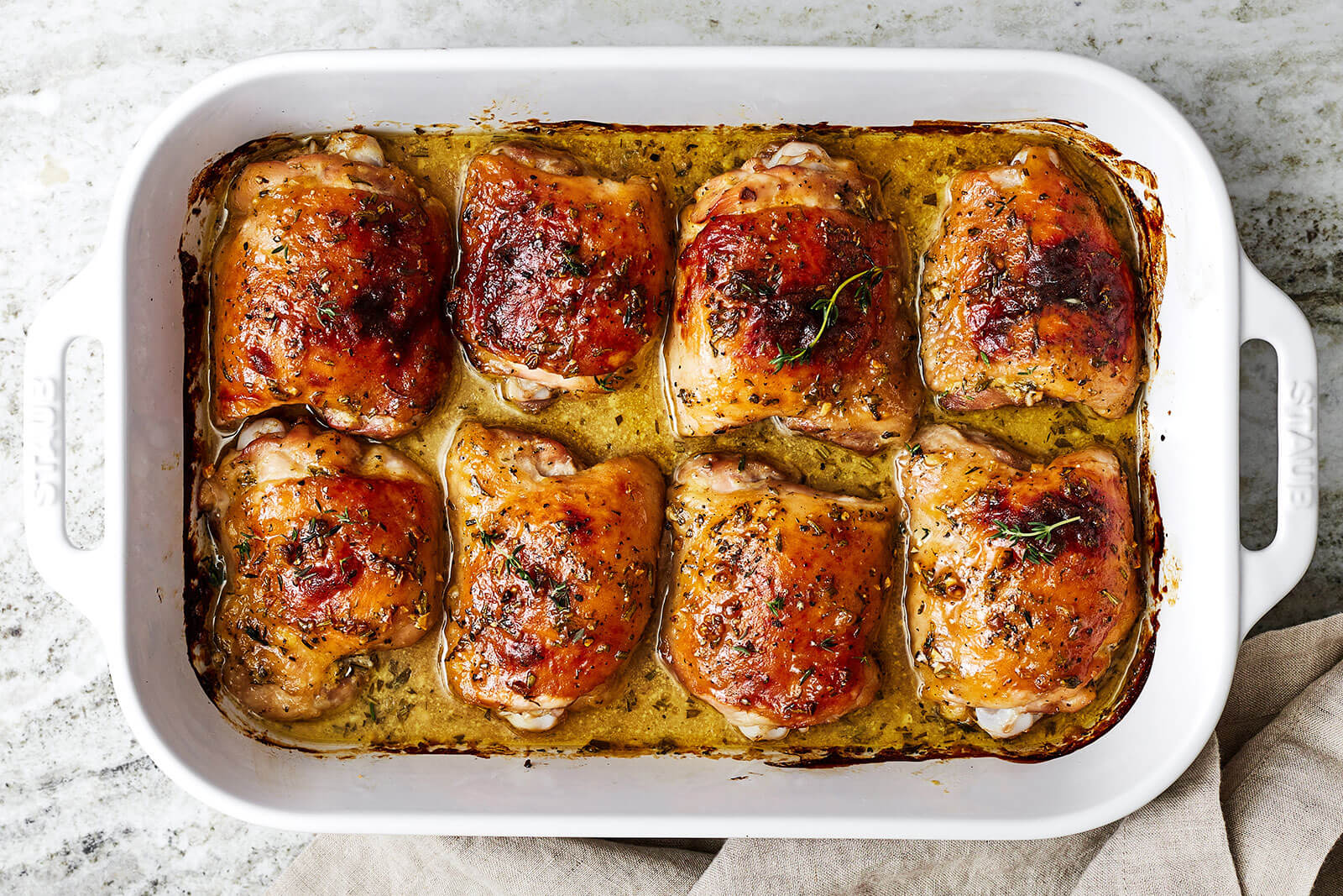 A casserole dish filled with baked honey mustard chicken thighs