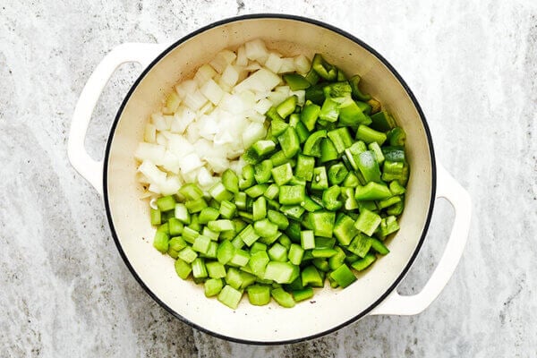 Adding veggies in a pot for jambalaya