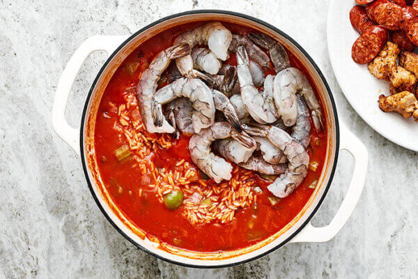 Adding shrimp into a pot of jambalaya