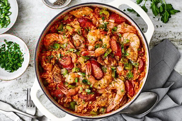 A big pot of jambalaya next to herbs