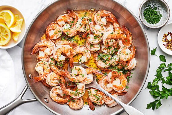 A metal pan of shrimp scampi with a spoon