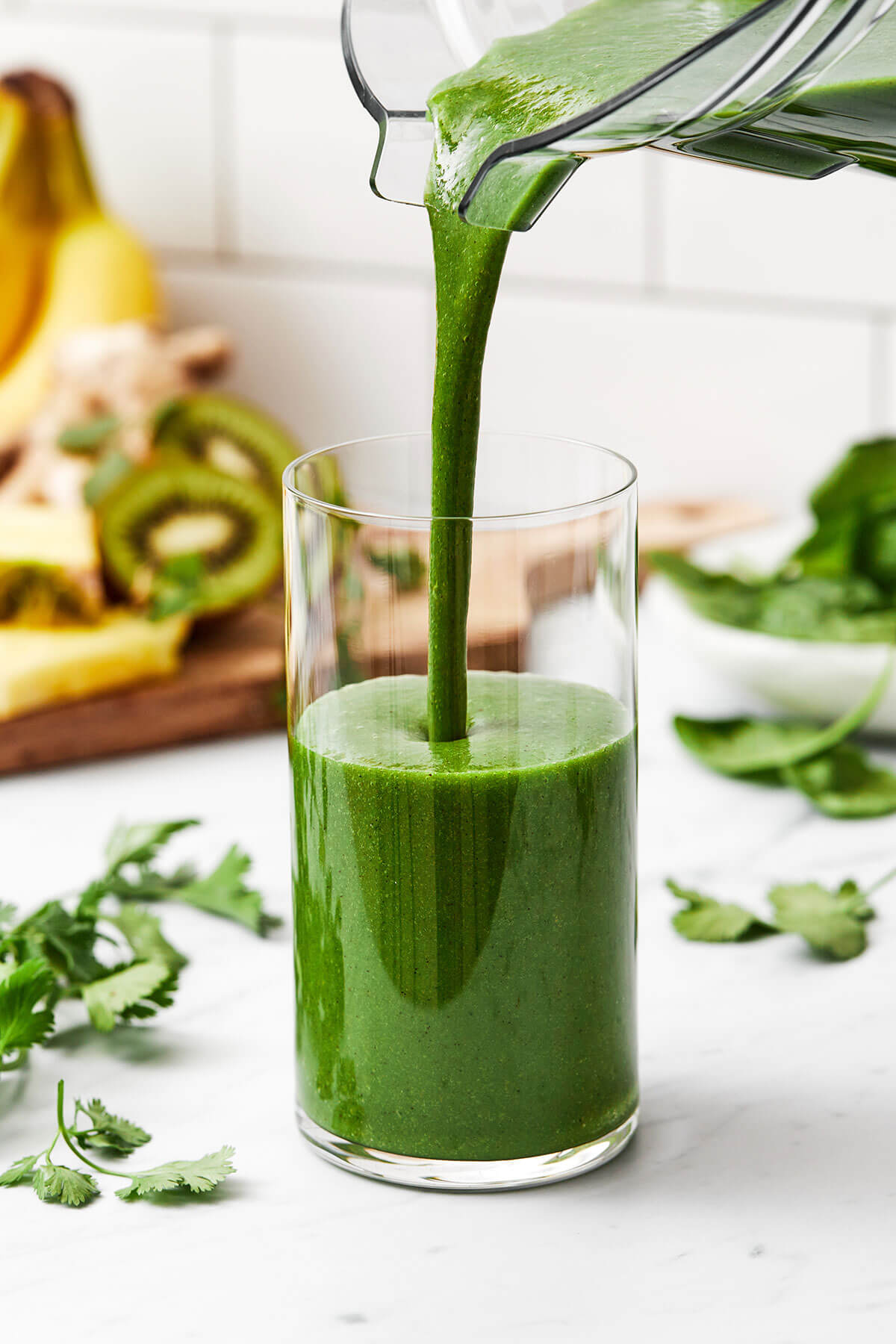 Pouring cilantro smoothie in a glass