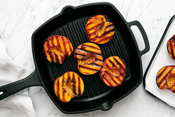 A cast iron grill pan with grilled peaches