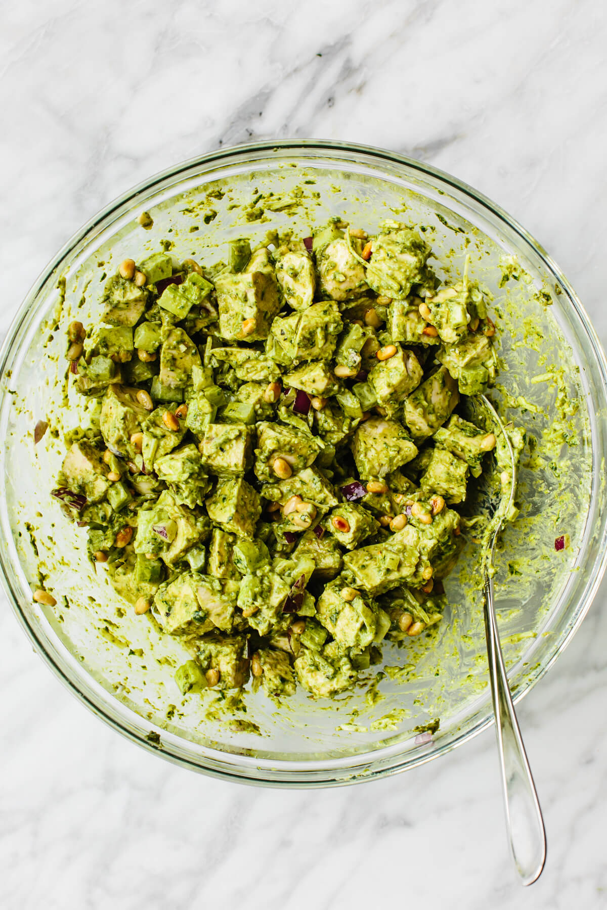 This pesto chicken salad is a fresh basil pesto spin on a classic that will undoubtedly be the summer salad of the season! Pesto chicken salad in a glass bowl