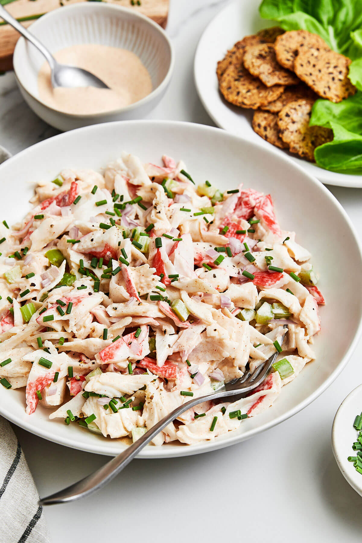 A bowl of crab salad next to crackers