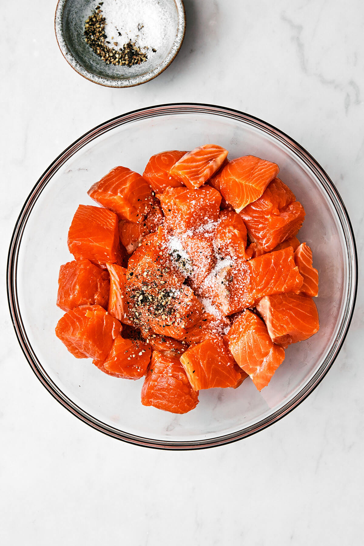 Mixing salmon cubes with salt and pepper in a bowl