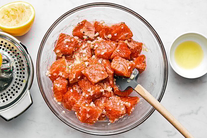 Mixing salmon cubes with a sauce