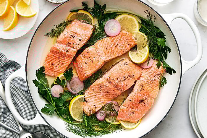 Poached salmon with herbs in a pan
