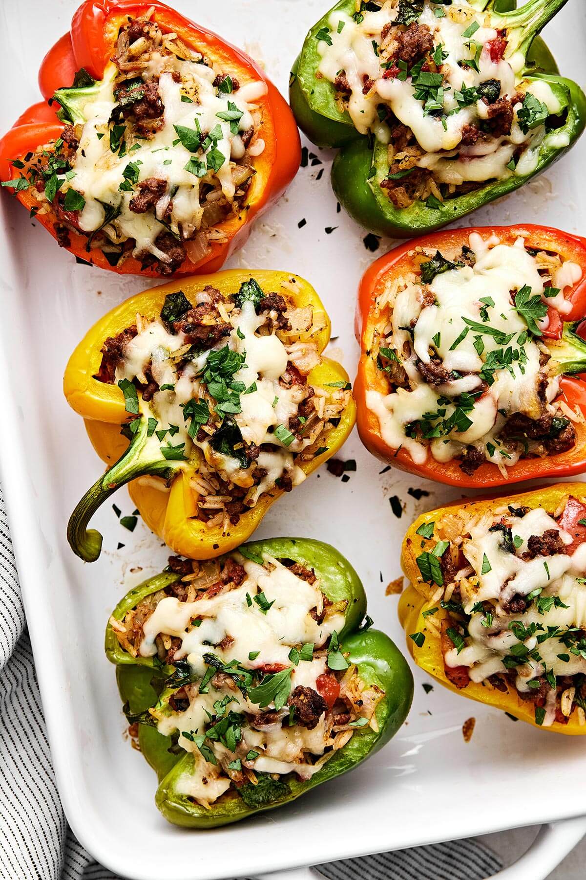Stuffed peppers are always a family favorite weeknight dinner. This classic version is packed with the best filling — juicy ground beef, fluffy rice, and plenty of veggies seasoned with Italian flavors. A baking dish filled with beef stuffed peppers.