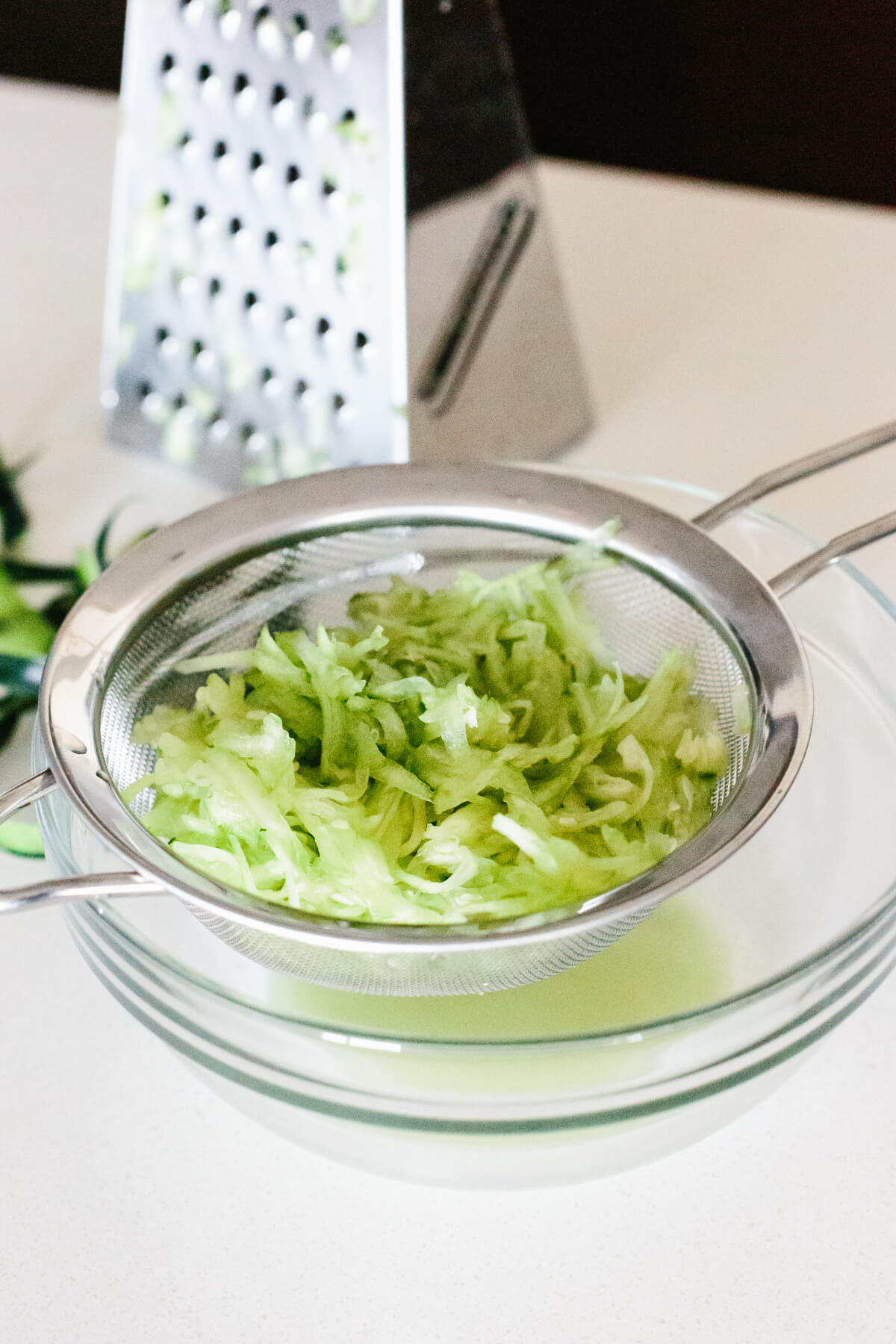Draining the liquid from grated zucchini.