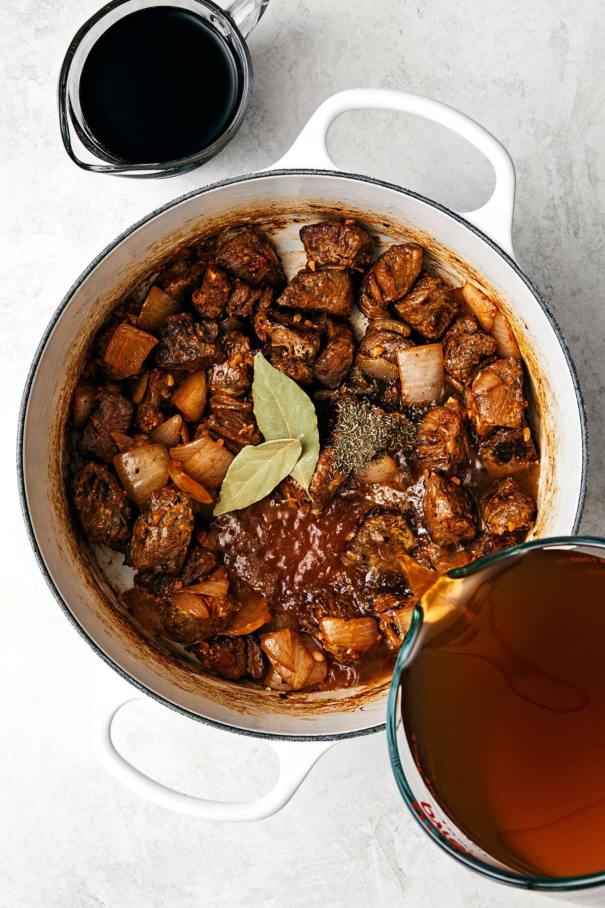 This classic beef stew recipe is a cold-weather one-pot wonder and my favorite for a hearty, comforting, and satisfying meal! Pouring broth into a pot with beef stew meat