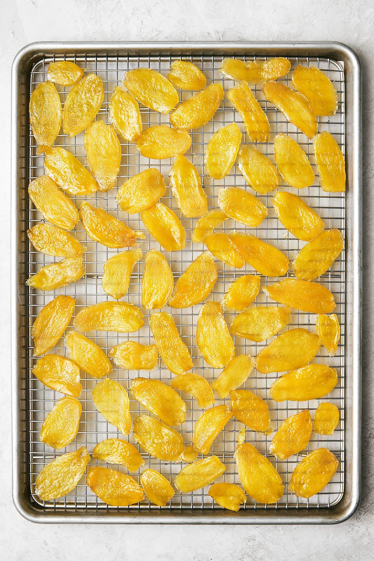 This easy homemade candied ginger is a tasty way to enjoy ginger while reaping all its shining health benefits! Drying candied ginger on a sheet pan