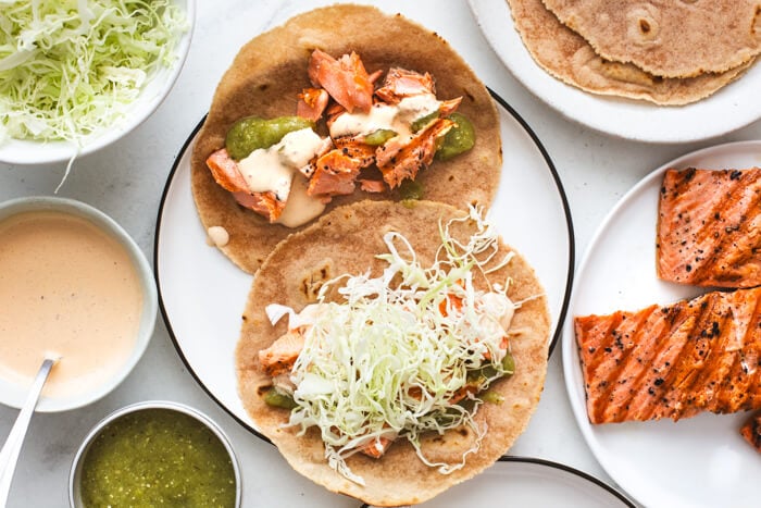 Assembling salmon tacos on a white plate