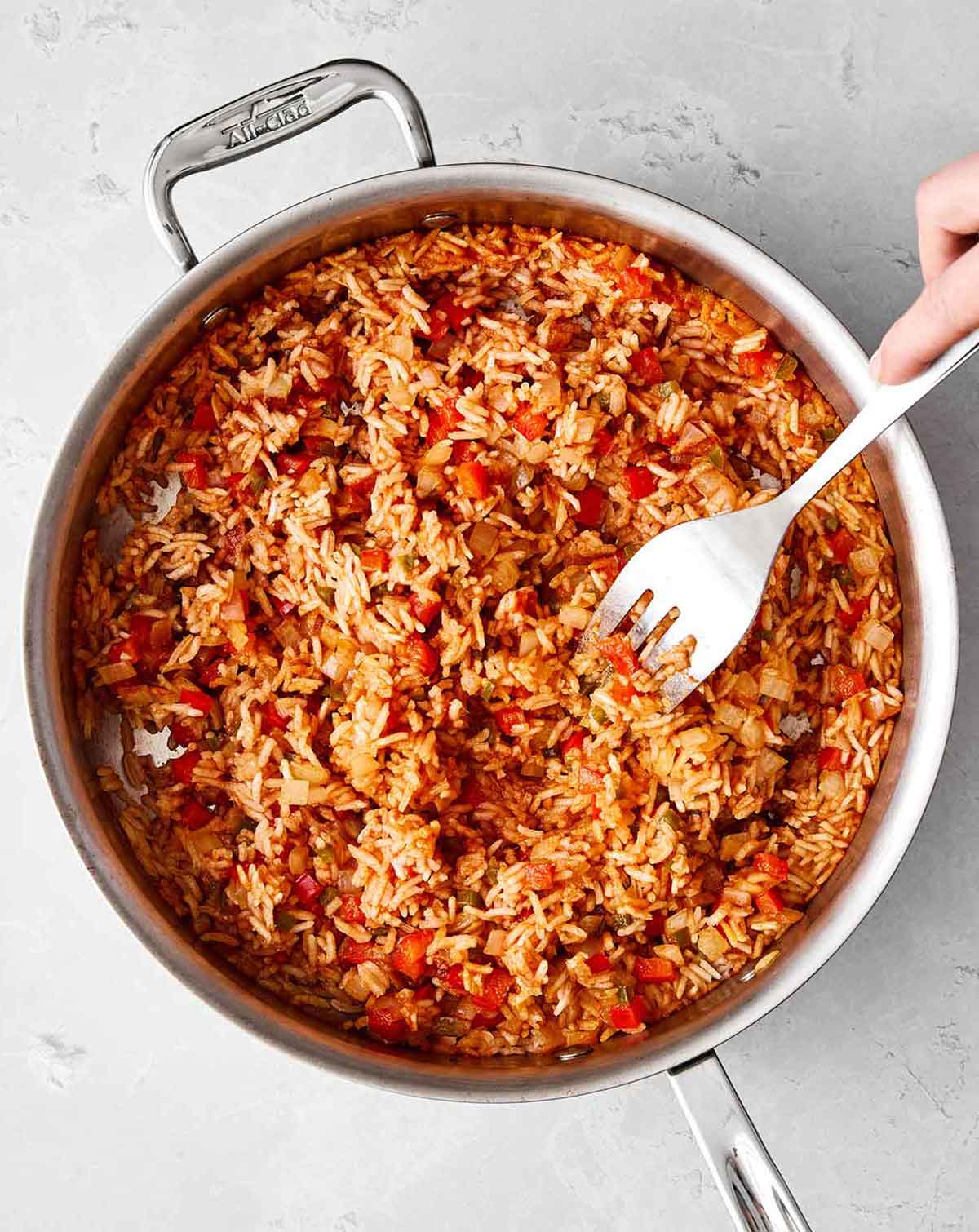 Fluffing Mexican rice in the pan before serving.