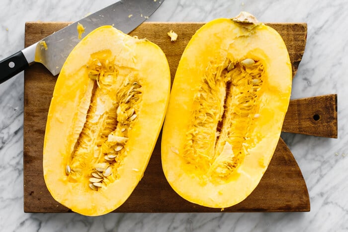 A spaghetti squash cut in half on a cutting board.
