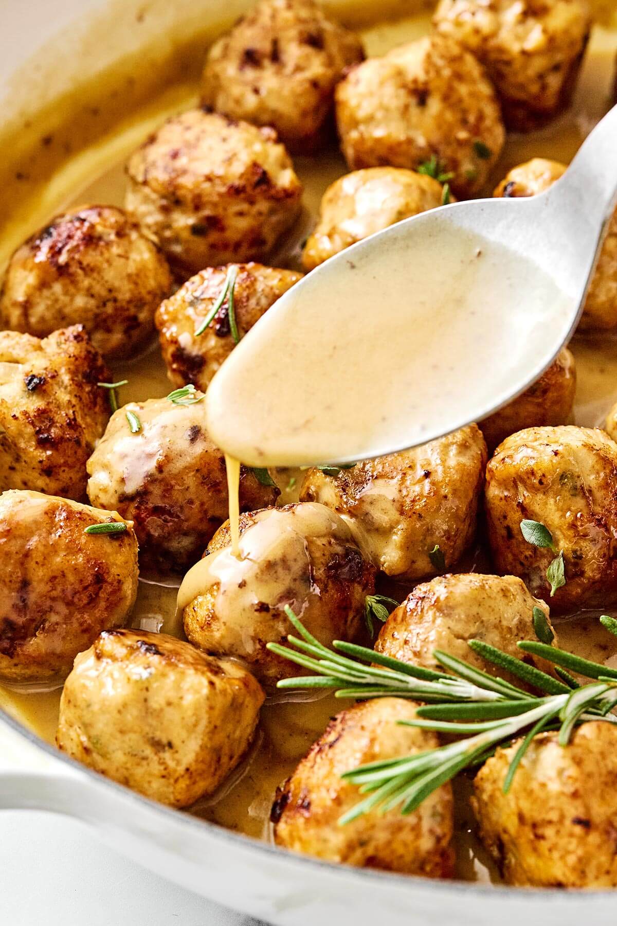 Drizzling sauce over turkey meatballs.
