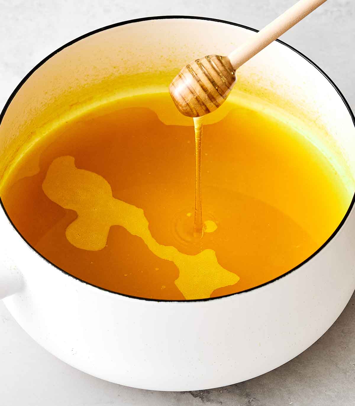 Second step to making turmeric tea by adding honey after it simmers on the stovetop.