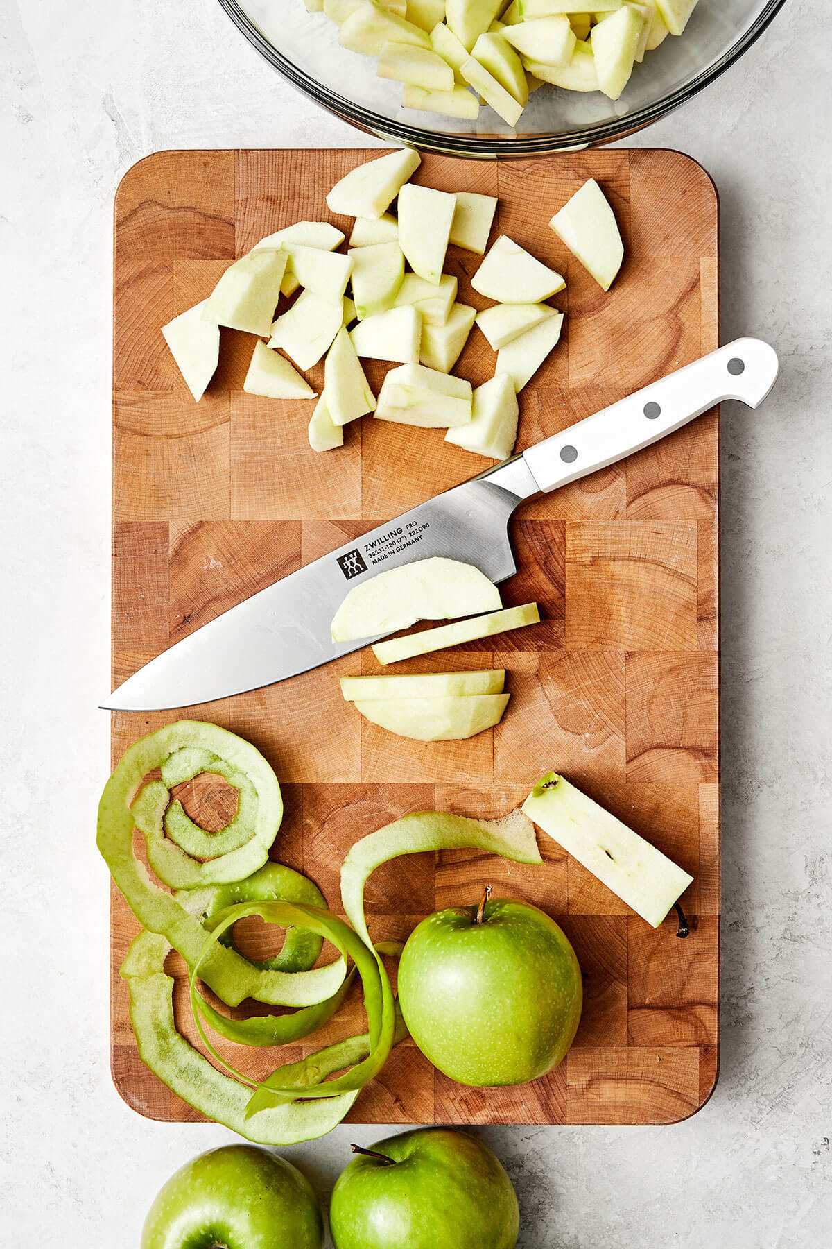 This apple crisp is the best holiday dessert with a sweet cinnamon apple filling and oat crumble topping — especially during Thanksgiving! Peeling apples on a wooden board.