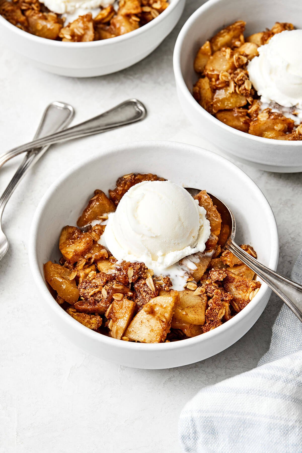 This apple crisp is the best holiday dessert with a sweet cinnamon apple filling and oat crumble topping — especially during Thanksgiving! A bowl of apple crisp with ice cream.