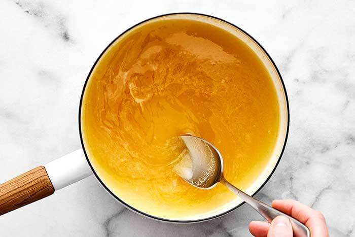 Mixing honey and orange juice in a pot.