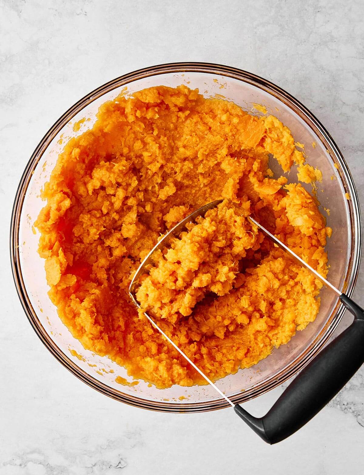 Mashing sweet potatoes in a bowl.