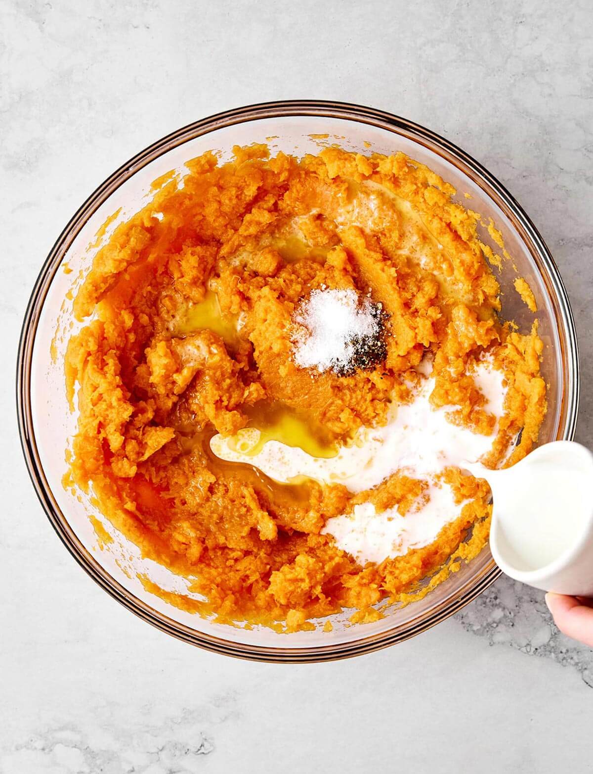 Adding milk to mashed sweet potatoes.