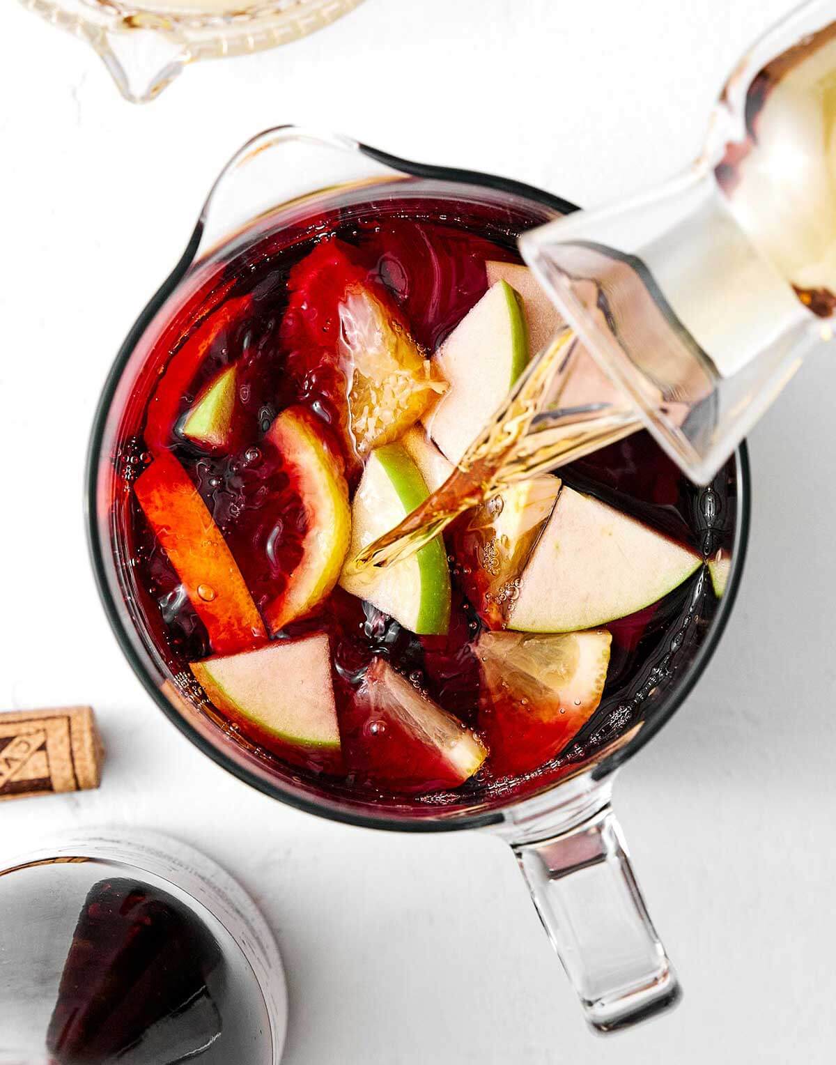 A pitcher of this red sangria feels is the perfect cocktail for a crowd! All you need is Spanish red wine, brandy, and fresh fruit. Pouring brandy into red sangria.