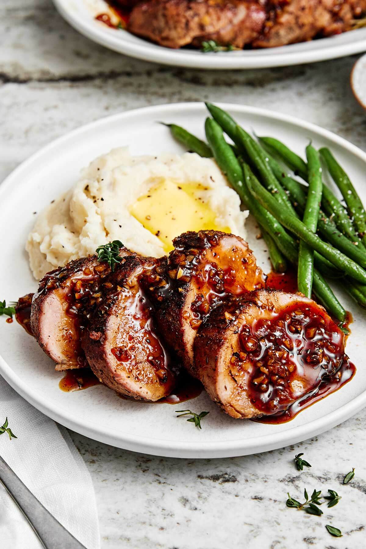 The juiciest pork tenderloin that's seasoned with a flavorful spice blend, seared to a golden crust, and baked with the best honey garlic sauce. Sliced pork tenderloin with mashed potatoes.