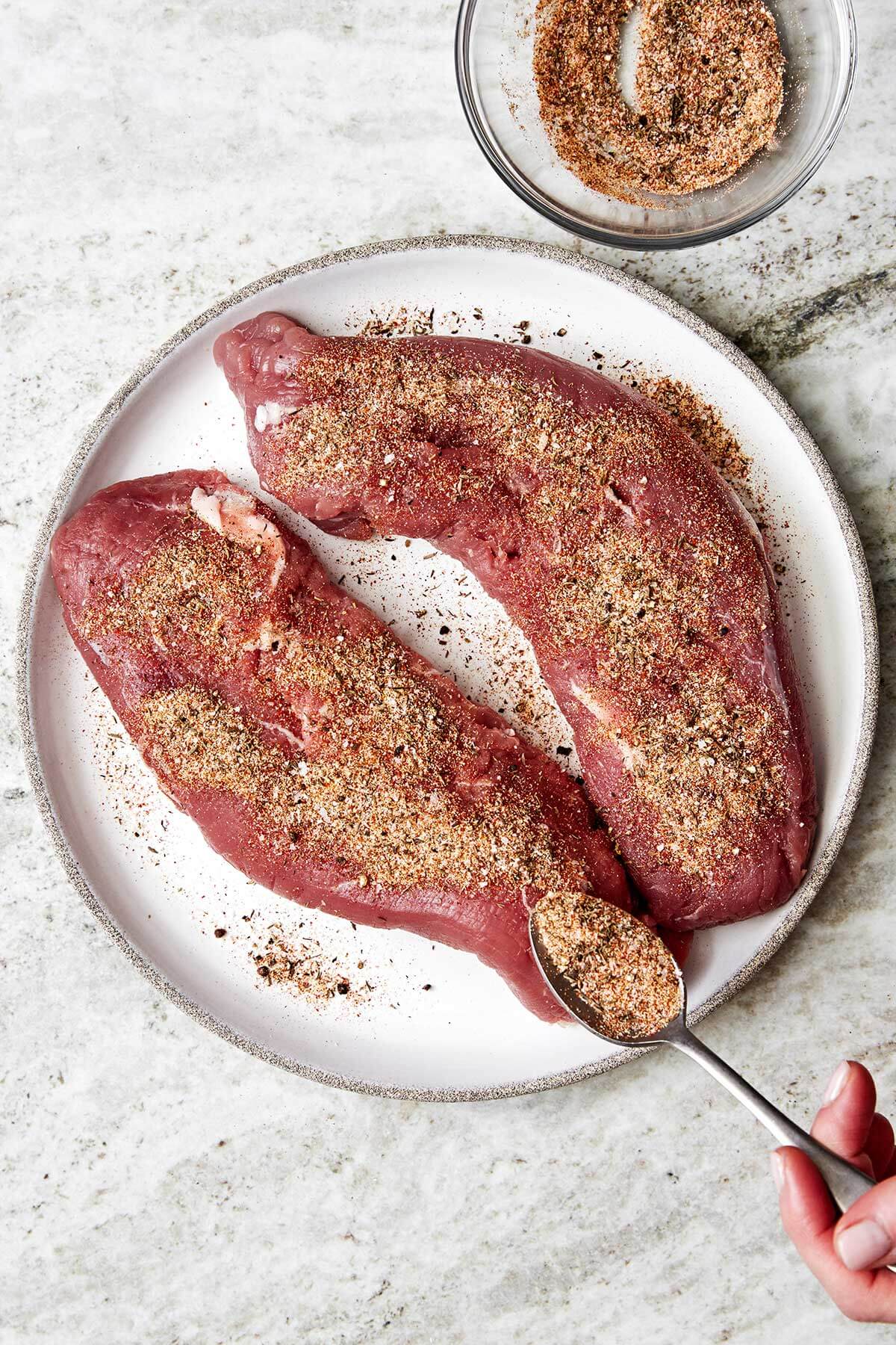 The juiciest pork tenderloin that's seasoned with a flavorful spice blend, seared to a golden crust, and baked with the best honey garlic sauce. Adding seasoning to pork tenderloin.