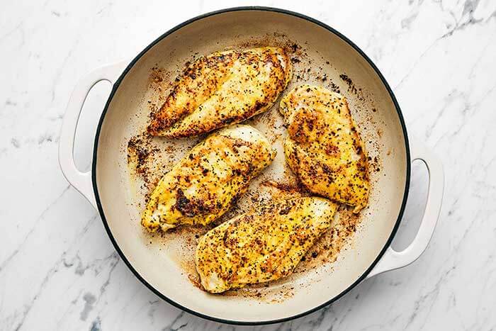 Cooking lemon pepper chicken in a pan.